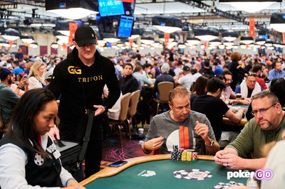 Jason Koon & Eric Afriat are seen sitting at a poker table at the WSOP Main Event 2022. Behind them, you can see a sea of other poker tables and players spread throughout the entire space.