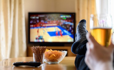 A man with his feet up watching basketball on Thanksgiving. Holiday Hoops: Best Basketball Thanksgiving Betting Predictions