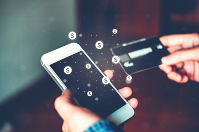 close up of a woman's hands. in one she holds a cell phone and in the other a credit card. dollar signs float above. BetMGM Sportsbook Banking: Deposits & Withdrawals Explained