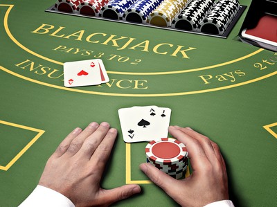 A casino blackjack table is seen from above with cards displayed, chips, dealer, and a player's hands. Blackjack Strategy: How to Win Blackjack at US Online Casinos