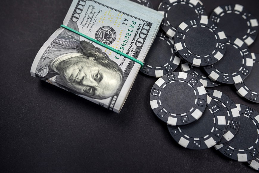 colored poker chips scattered with a roll of US dollars isolated on a black background -- How to Deposit and Withdraw at Online Casinos in the US