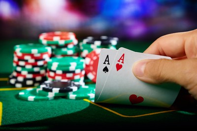 Player showing cards at poker table. Winning hand of a pair of Aces. Invest in Yourself: How Much Does It Cost to Improve at Poker?