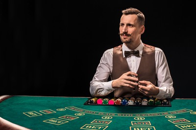 Croupier with mustache stands behind gambling table in a live casino studio. Why Live Dealer is the Future of Online Casinos