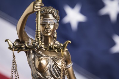 The statue of justice Themis or Justitia, the blindfolded goddess of justice against a flag of the United States of America. US Supreme Court Grants Stay in Florida Sports Betting Case