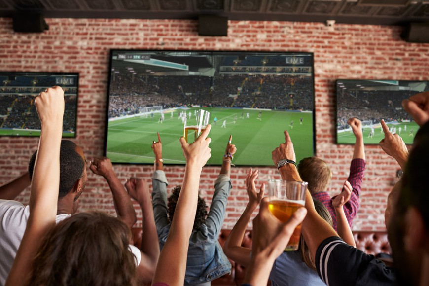 Rear View Of Friends Watching Soccer/Football Game In Sports Bar. Bluegrass Bets: Kentucky Legal Sports Betting Goes Live!