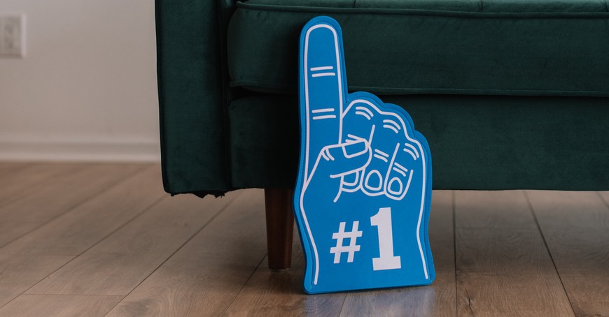 Blue foam finger with a #1 on it sits on floor next to green couch. #1 NFL Promo for Casual Bettors: BetMGM's Bet $10, Get $200