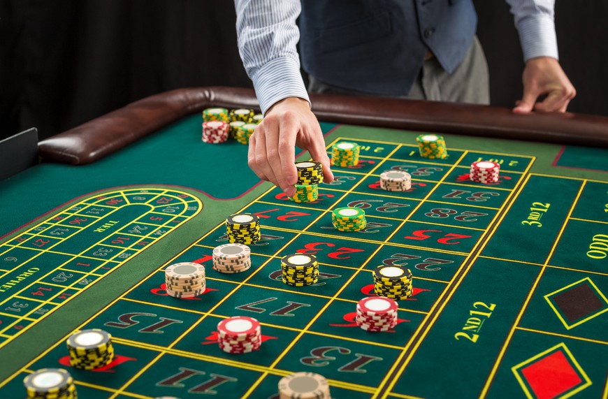 Close up of a green roulette table with chips on it. A man's hand is seen placing chips on the table. Online Casinos vs. Traditional Casinos: Which Are Better?