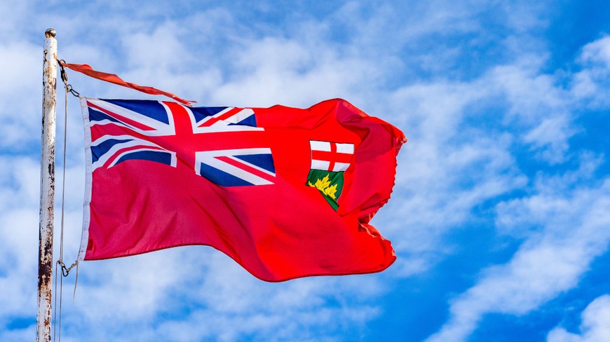 Ontario flag flies against a blue sky with fluffy white clouds. On April 4, 2022, the regulated iGaming market in Ontario will open, allowing legal private-owned online poker, casinos, and sportsbooks to operate.