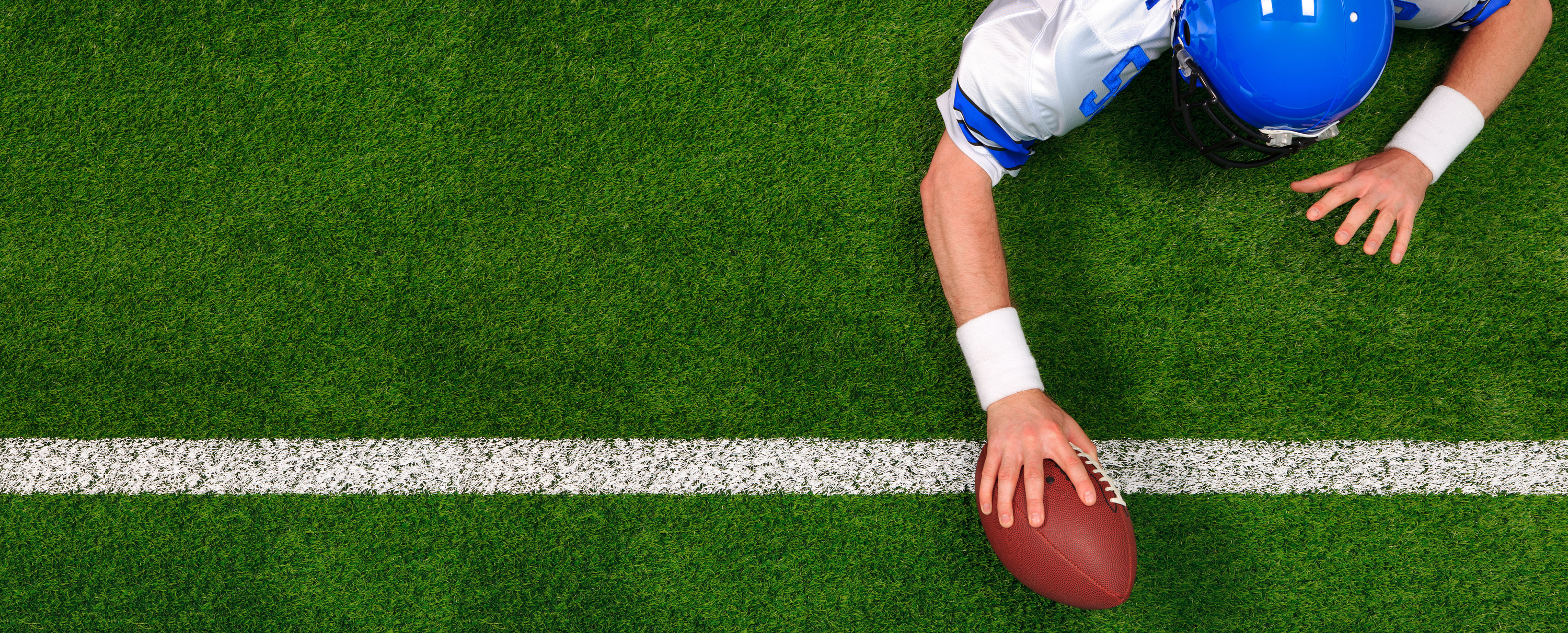 Overhead photo of an American football player making a one handed touchdown. Sports Betting 101: How Does Over/Under Sports Betting Work