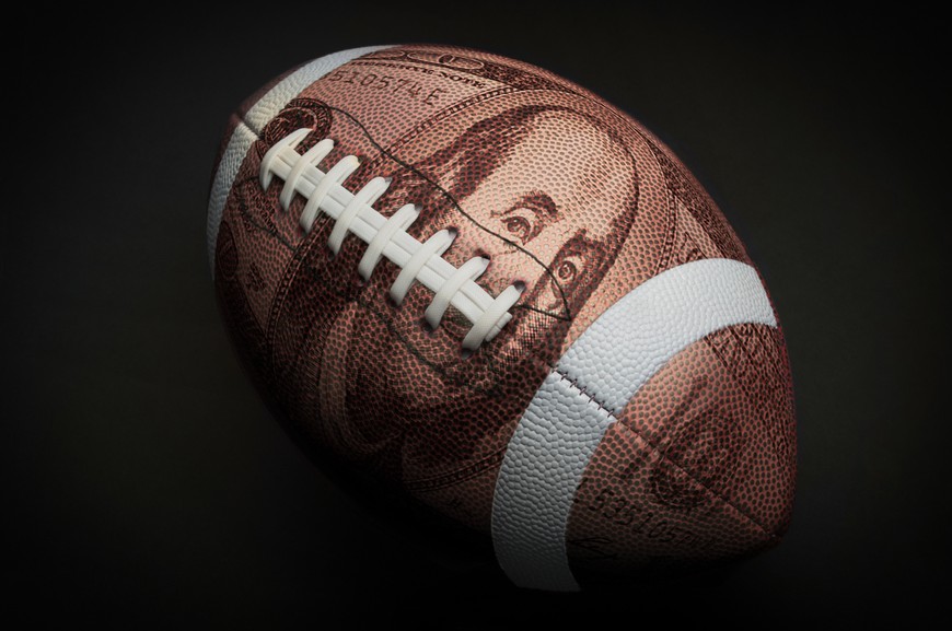 A football with a $100 bill superimposed, illustrating the sports betting bonuses you can signing up at NJ sportsbooks.