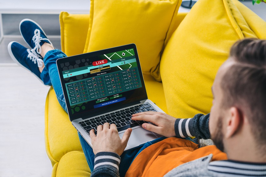 Cropped shot of a man lying on sofa making bets online at bookmaker's website using laptop. Which Sportsbook Has the Best Odds?